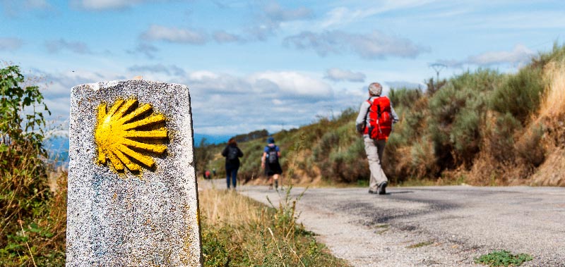 peregrinos haciendo el camino de santiago con mojon